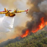 un avión de extinción descarga agua sobre un incendio forestal ardiendo en un bosque