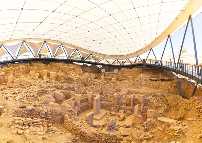 varias estelas y círculos de piedra en el santuario de Göbeklitepe, observados por turistas