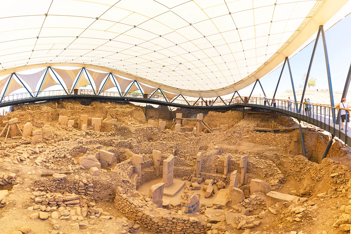 varias estelas y círculos de piedra en el santuario de Göbeklitepe, observados por turistas