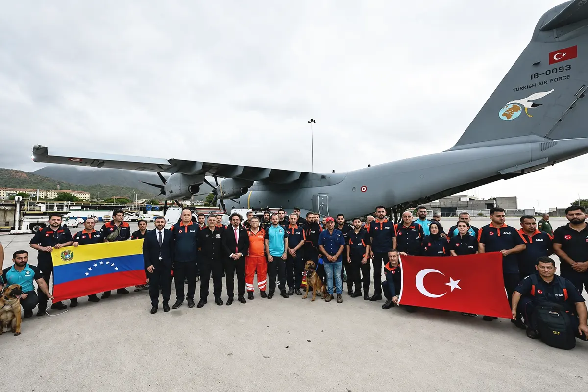 Rescue teams sent by Turkey following the earthquake in Venezuela pose at the airport with the flags of both countries next to a Turkish Air Force aircraft