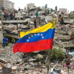 a Venezuelan flag next to a building that collapsed in the earthquakes, filled with rescue workers