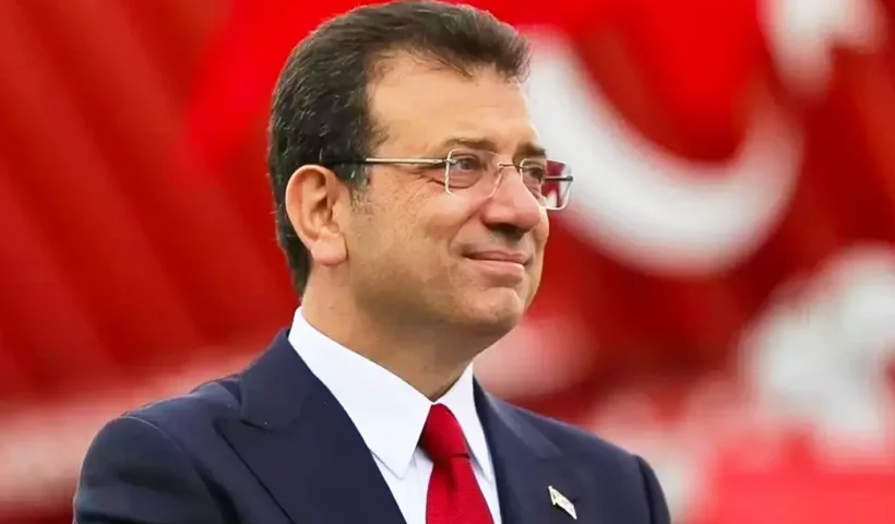 una imagen de İmamoğlu vistiendo traje y corbata y sonriendo sobre un fondo rojo