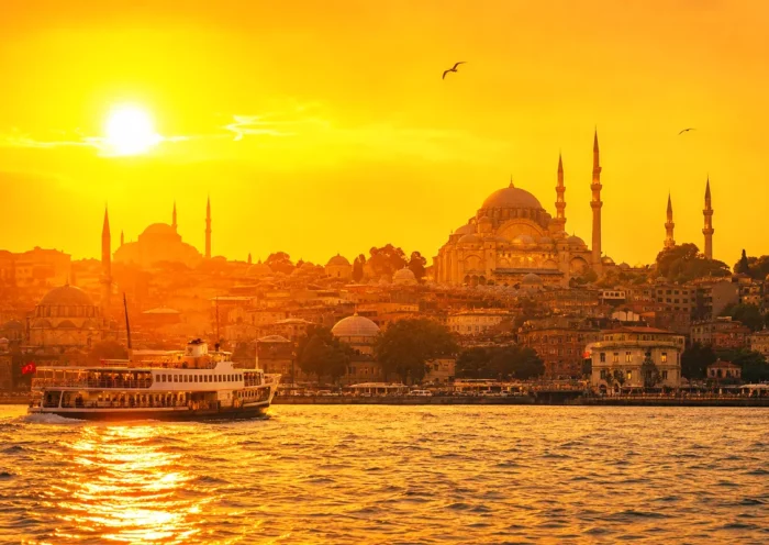 una imagen de varios edificios de Estambul a orillas del Cuerno de Oro durante el atardecer, con tonos anaranjados y ocres, en medio de un día caluroso