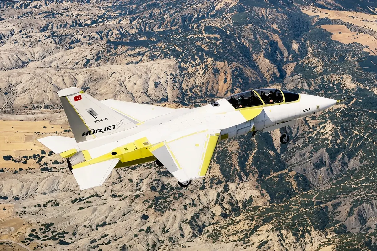 a Turkish Hürjet fighter prototype in light colours flying over a landscape in inland Anatolia
