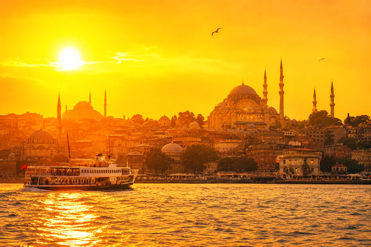 a picture of several buildings in Istanbul on the banks of the Golden Horn at sunset, bathed in shades of orange and ochre, on a hot day