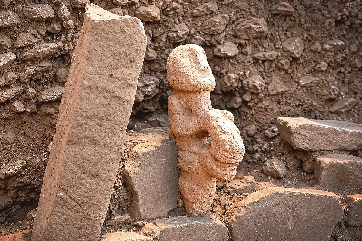 a human-shaped stone statue next to some stones at an archaeological site