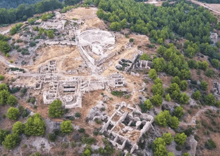 aerial view of some Roman ruins on a mountain surrounded by woods