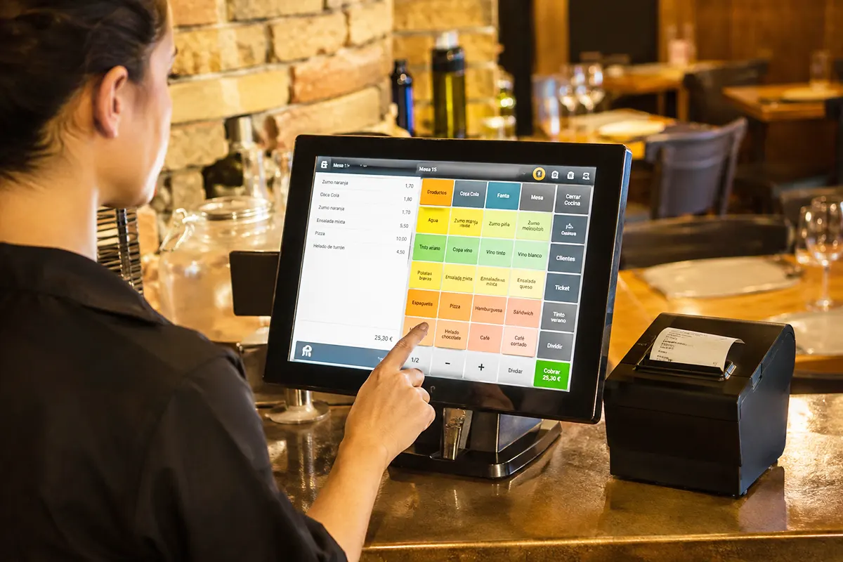 una camarera manejando en una pantalla de un restaurante un software TPV de gestión de pedidos