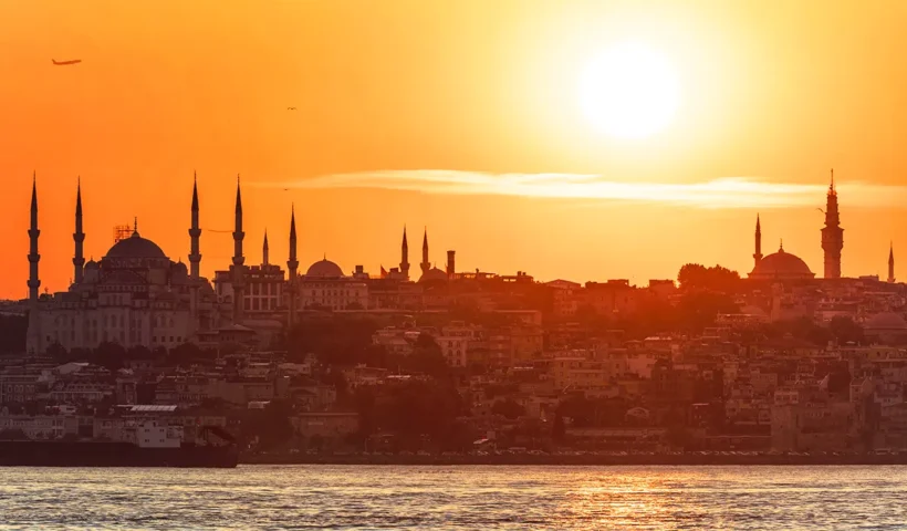 silueta de Estambul desde el Bósforo con tonos dorados y el sol en lo alto