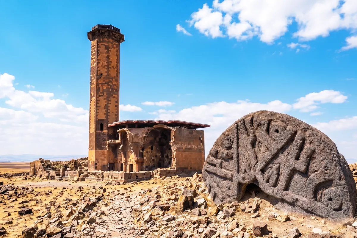 A composite image featuring an ancient stone stele bearing ancient inscriptions along the first mosque in Anatolia, situated amongst the ruins of Ani