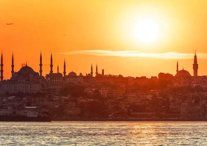 the silhouette of Istanbul from the Bosphorus, bathed in golden hues, with the sun high in the sky