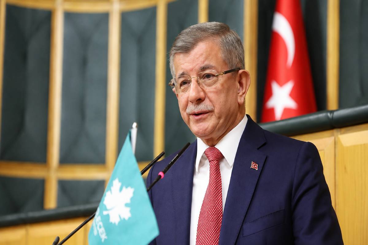 Former Turkish Prime Minister Ahmet Davutoğlu, speaking in public from the parliament building alongside a Turkish flag and a flag of his Future Party