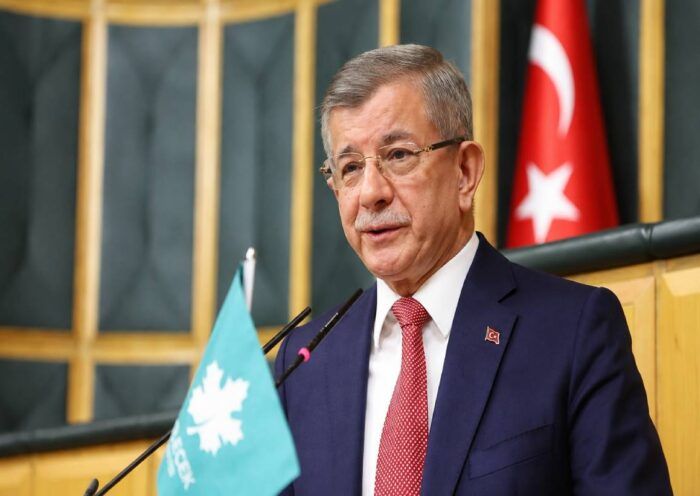 el ex primer ministro turco Ahmet Davutoğlu, hablando en público desde la sede del parlamento junto a una bandera de Turquía y de su Partido del Futuro