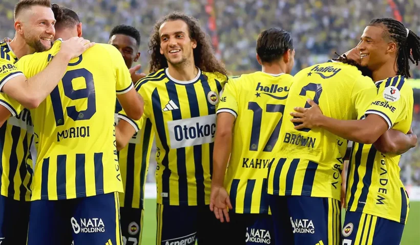 Fenerbahçe players embracing each other joyfully after a goal
