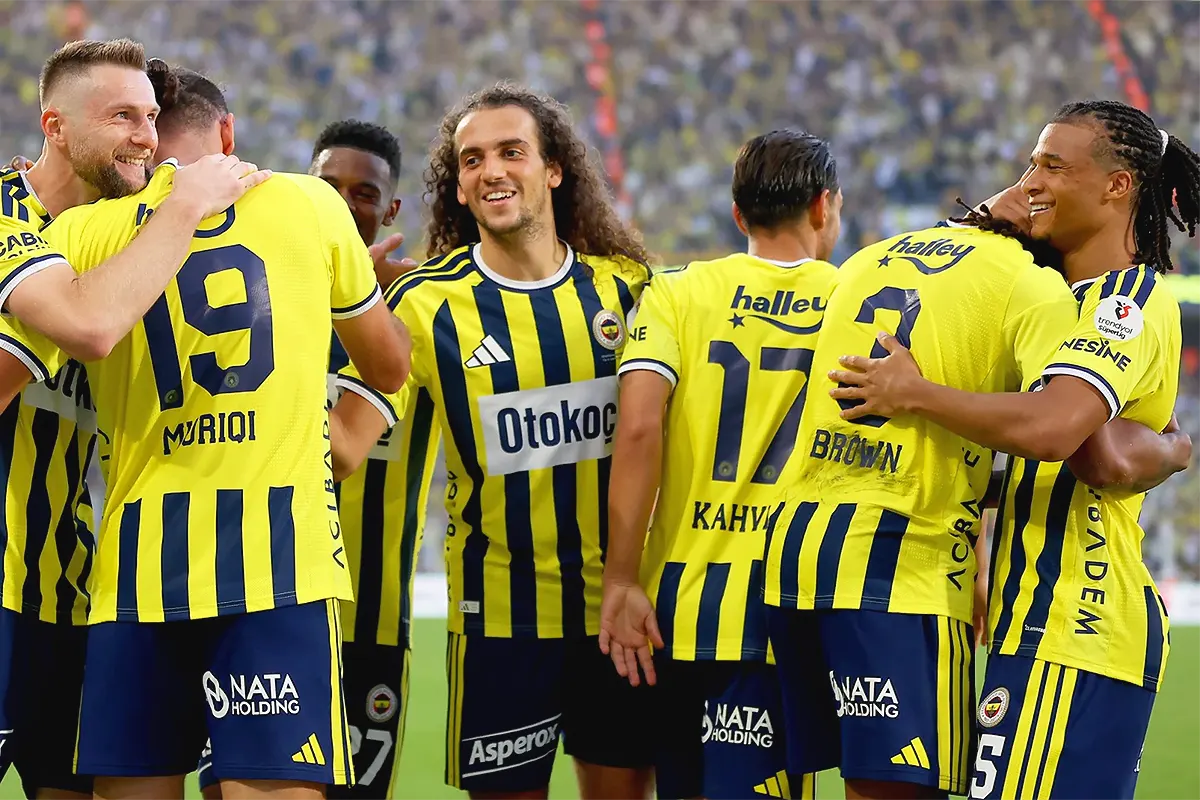 Fenerbahçe players embracing each other joyfully after a goal