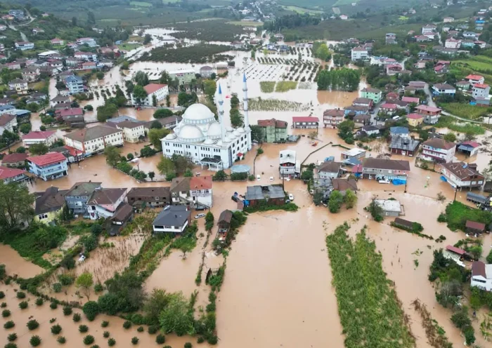 an aerial view of a small Turkish village with a mosque in the centre and a massive flood covering the streets and fields