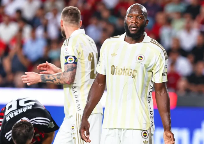 Fenerbahçe players alongside a Gaziantep FK player crouching on the pitch