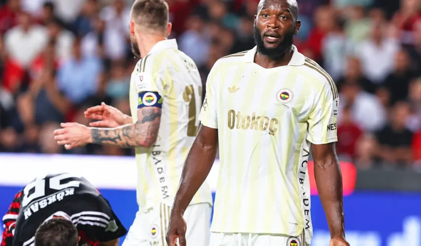Fenerbahçe players alongside a Gaziantep FK player crouching on the pitch