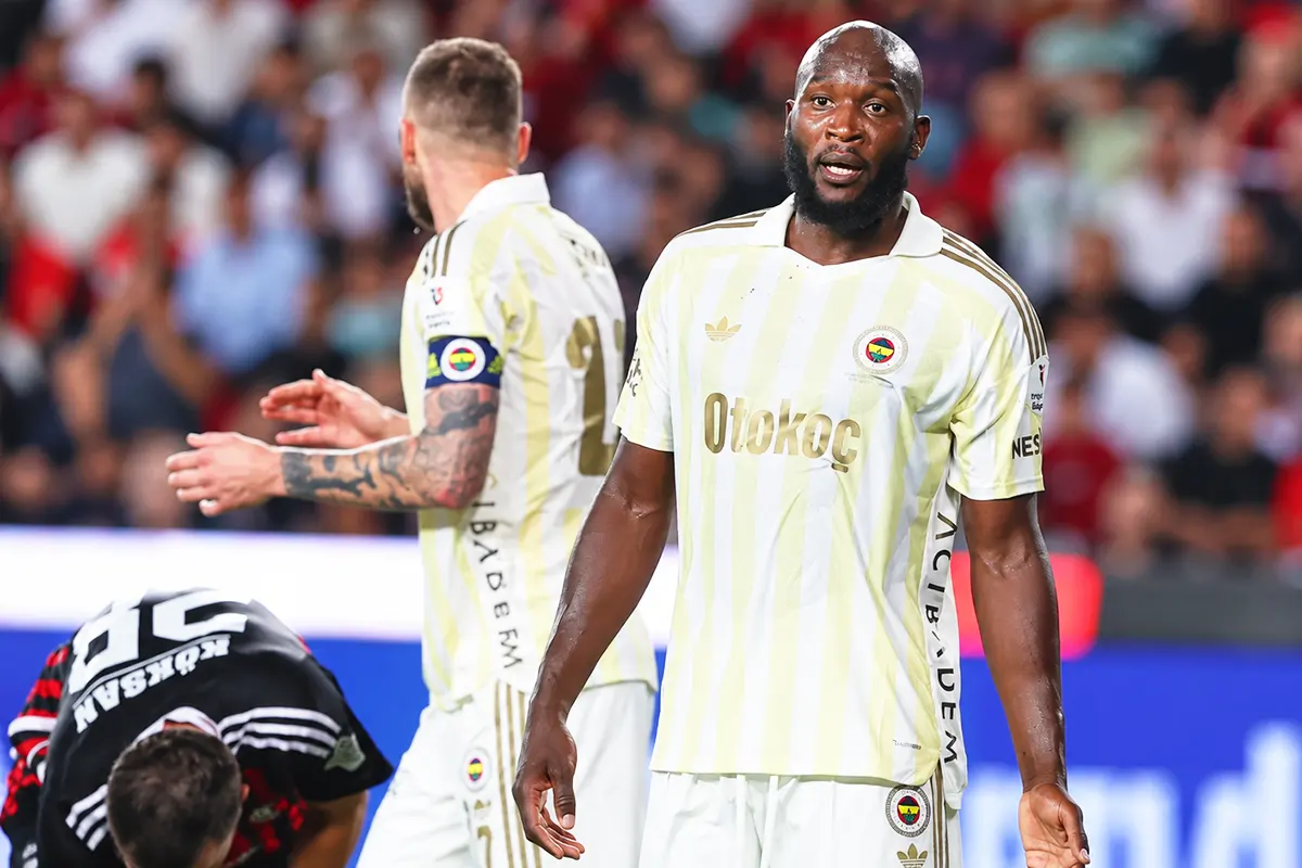 Fenerbahçe players alongside a Gaziantep FK player crouching on the pitch