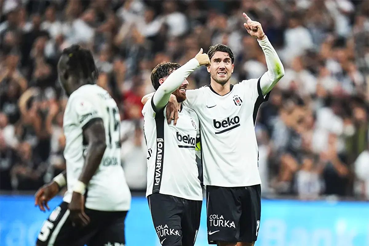 Two Beşiktaş players embrace and point to the sky after scoring a goal