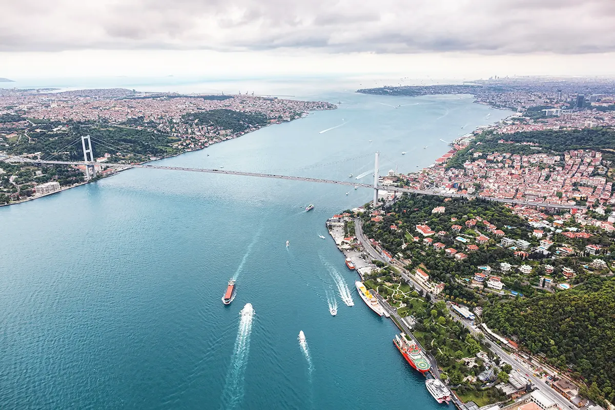 aerial view of the Bosphorus Strait in Istanbul, with several ships crossing it alongside one of the bridges linking Europe and Asia