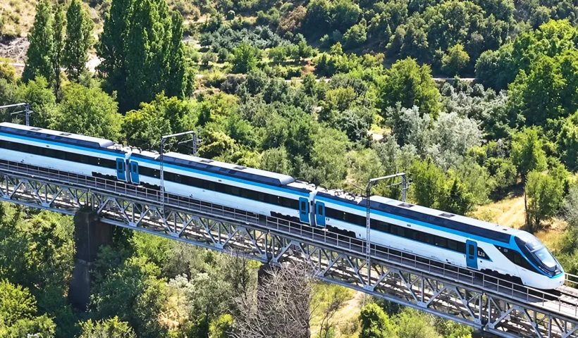 el tren de alta velocidad turco circulando sobre un puente rodeado de bosques