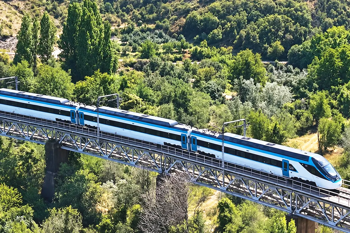 el tren de alta velocidad turco circulando sobre un puente rodeado de bosques