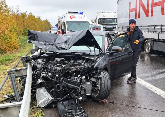 un coche completamente destrozado junto a una carretera siendo remolcado