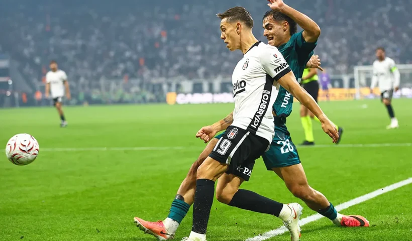 un jugador del Beşiktaş y otro del Kocaelispor disputándose el balón junto a la línea de banda en un estadio abarrotado de noche