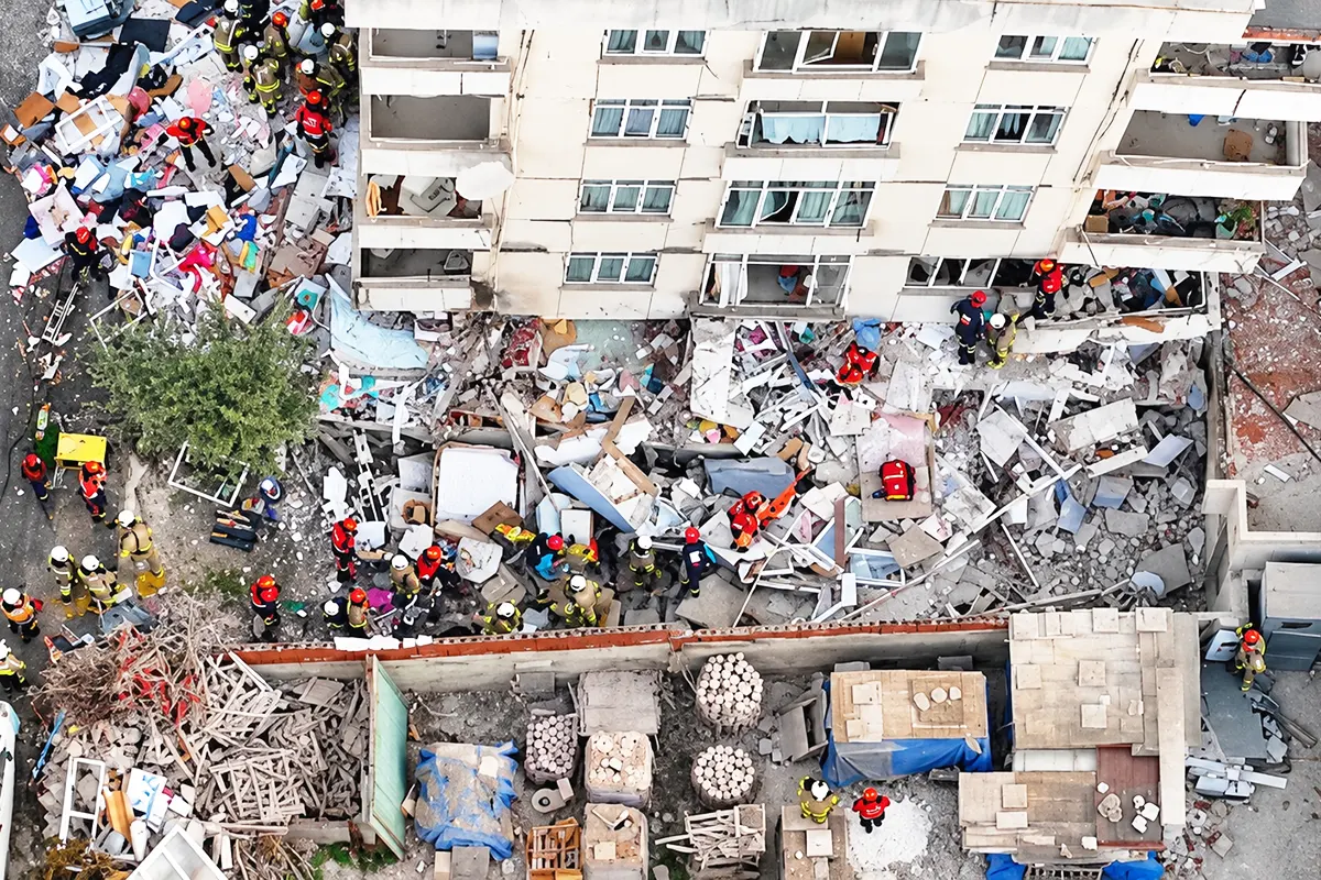 aerial view of several rescue workers at work amongst the ruins of a collapsed building