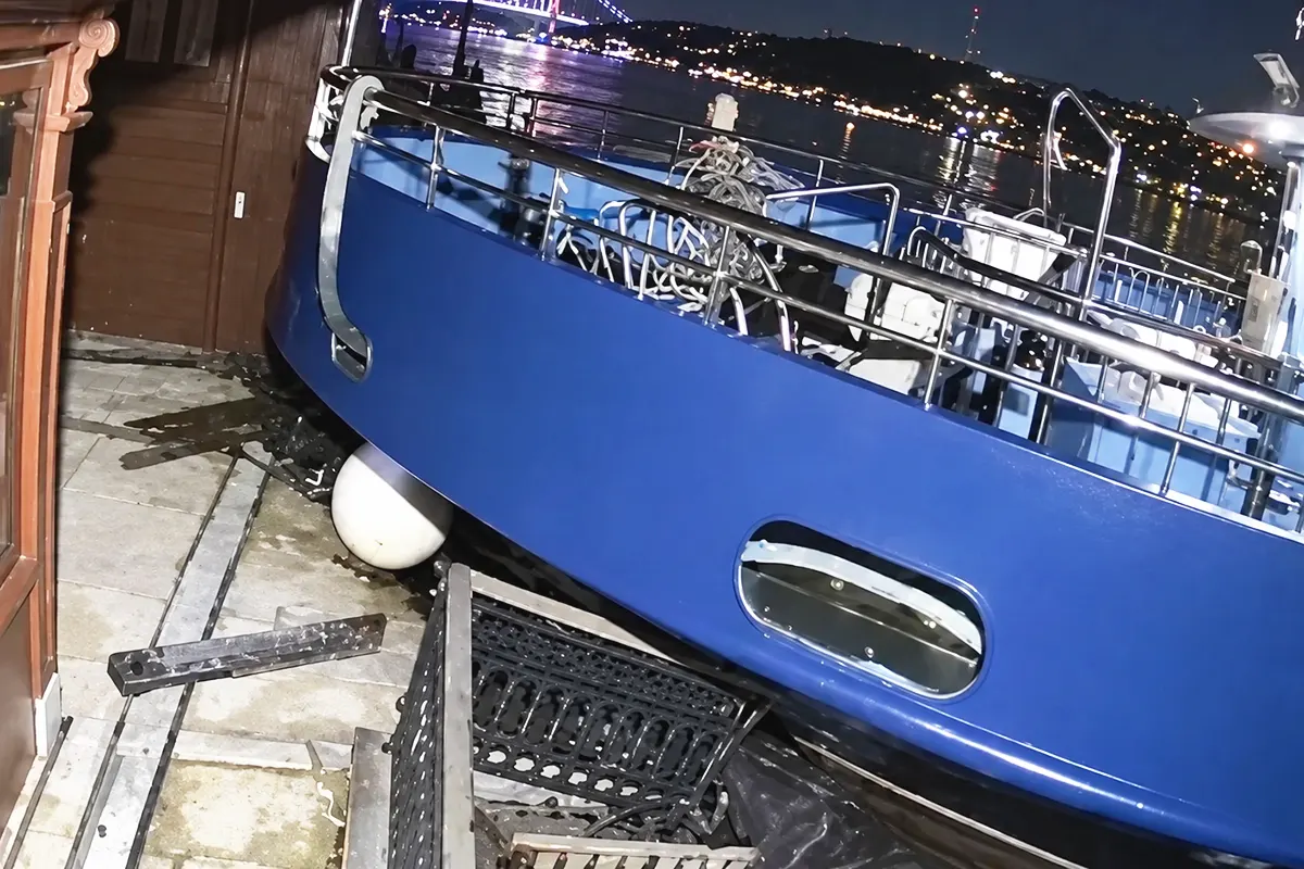 the bow of a blue ship crashing into and mounting a quay in the middle of the night