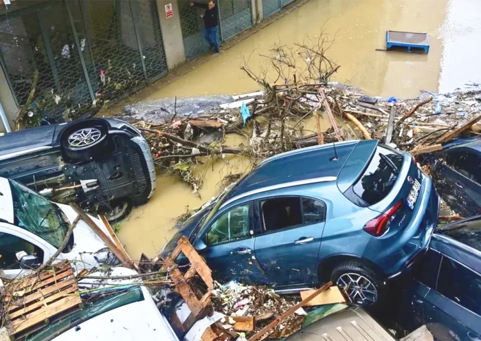 varios coches amontonados en una calle inundada junto a escombros y restos arrastrados por una riada