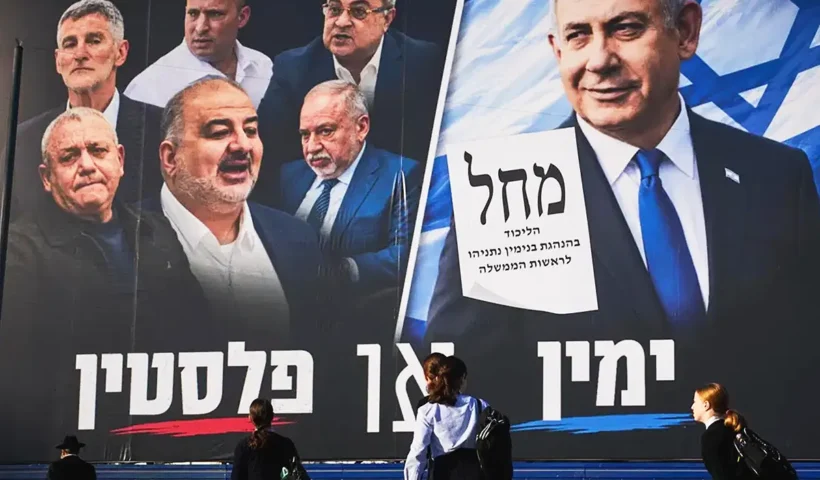 varias personas caminan junto a un cartel electoral que muestra a Netanyahu mirando desafiante a políticos de la oposición y de la minoría árabe