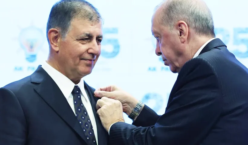Erdoğan pinning an AKP party badge onto the lapel of the mayor of Izmir, Cemil Tugay