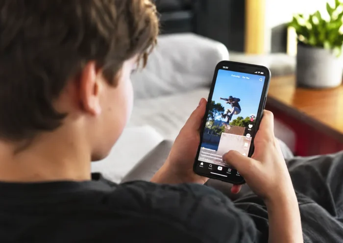 un menor sentado de espaldas viendo un vídeo en redes sociales