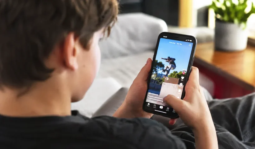 un menor sentado de espaldas viendo un vídeo en redes sociales