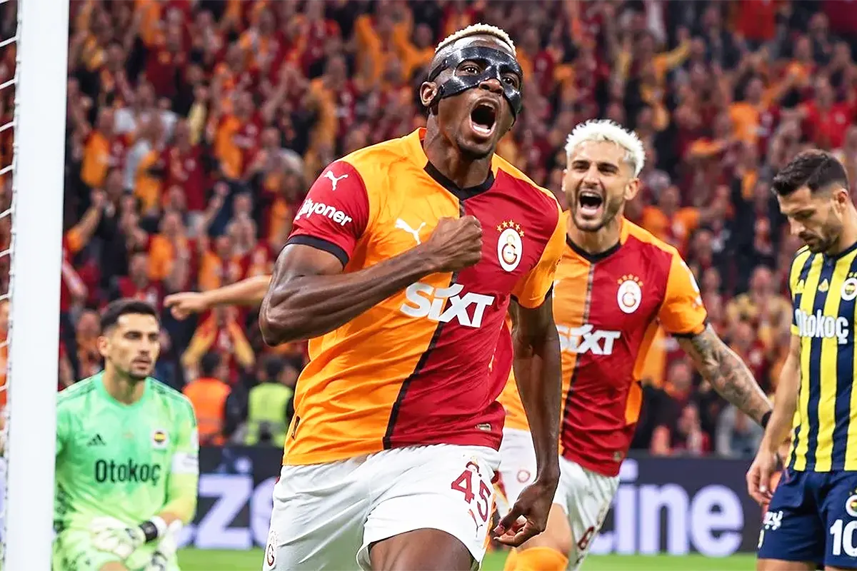 Osimhen celebrates a goal in front of the opposition’s goal; in the background, the goalkeeper and a Fenerbahçe player look dejected