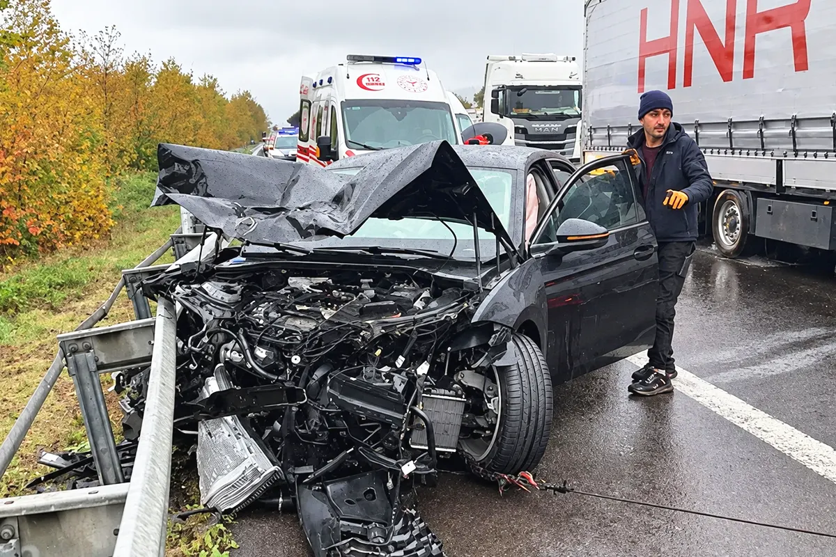 a car that has been completely wrecked, lying by the side of the road whilst being towed